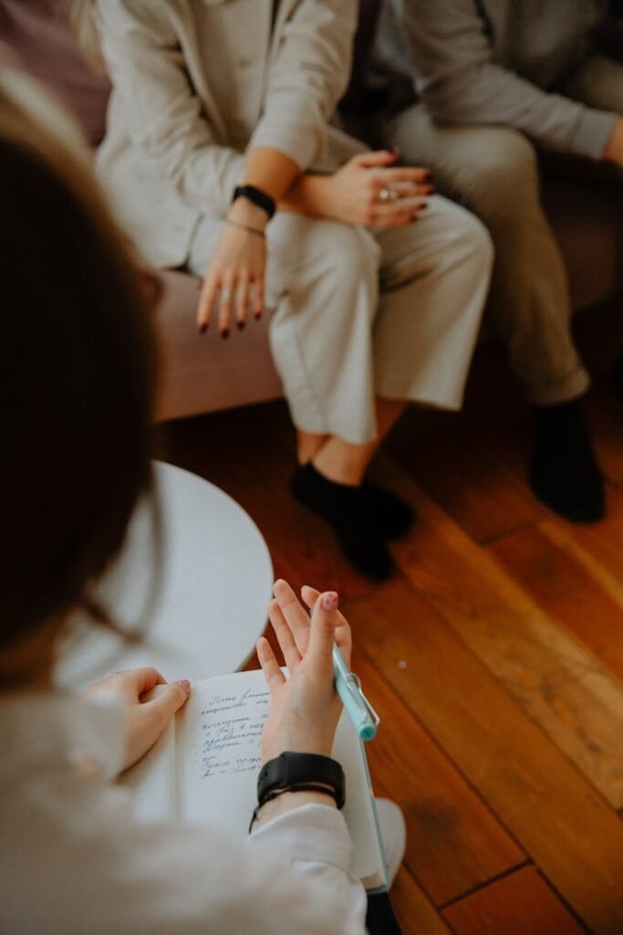 pexels photo 3958374 A therapy session with a counselor taking notes while clients discuss issues on a couch.